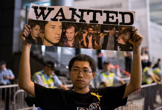 Một người biểu tình giơ cao poster với hình ảnh của nhân viên cảnh sát bị nghi là đã tham gia vào việc đánh đập người biểu tình ủng hộ dân chủ tại Hồng Kông vào ngày 15 tháng 10 năm 2014  AFP photo